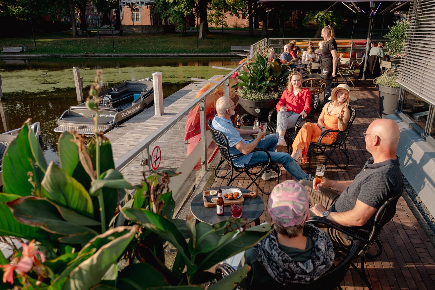 mensen op een terras aan het water met drankjes